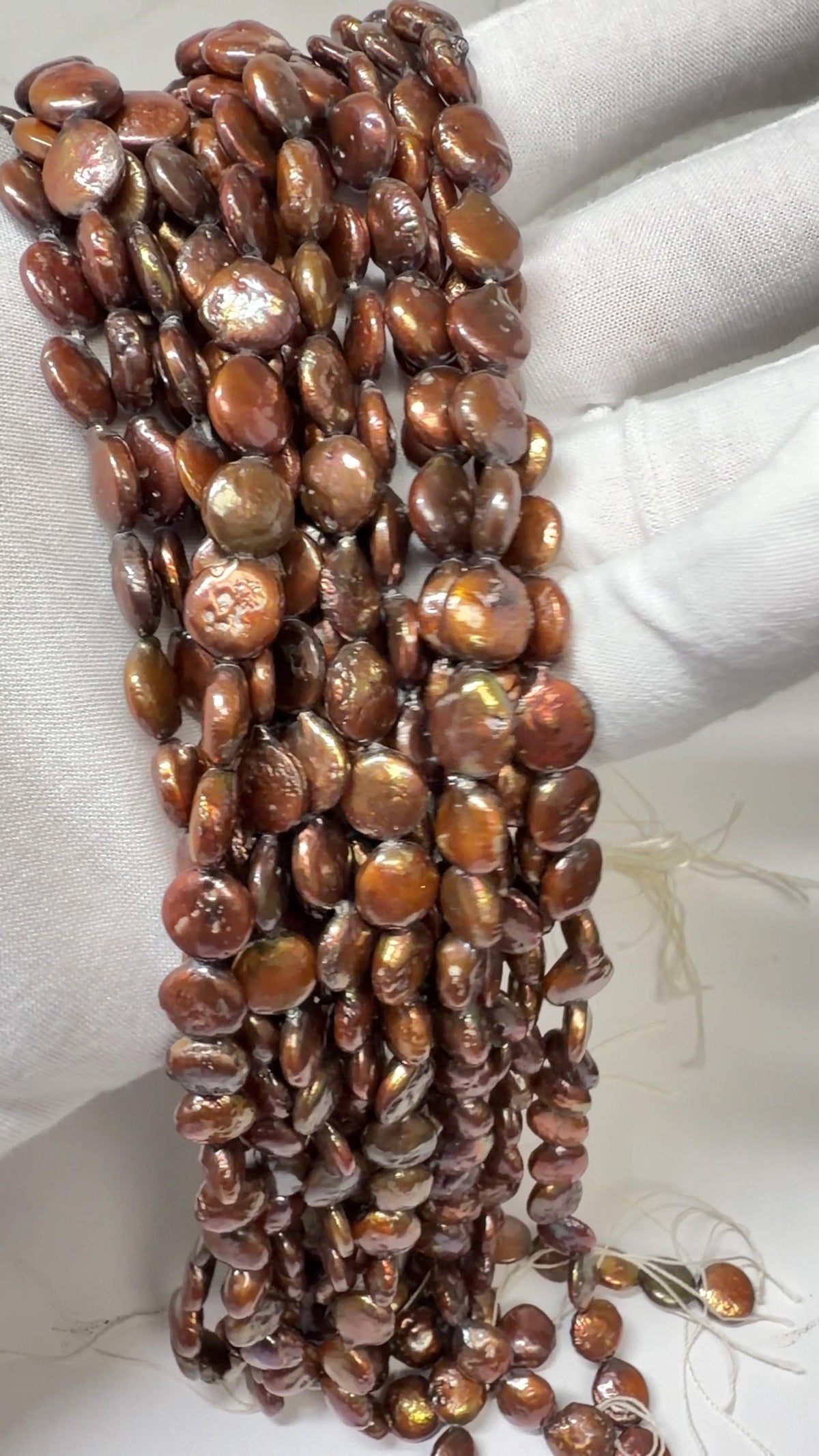 Coin Pearls Chocolate Color approx. 10mm, 15" strands! Draped on a white gloved hand