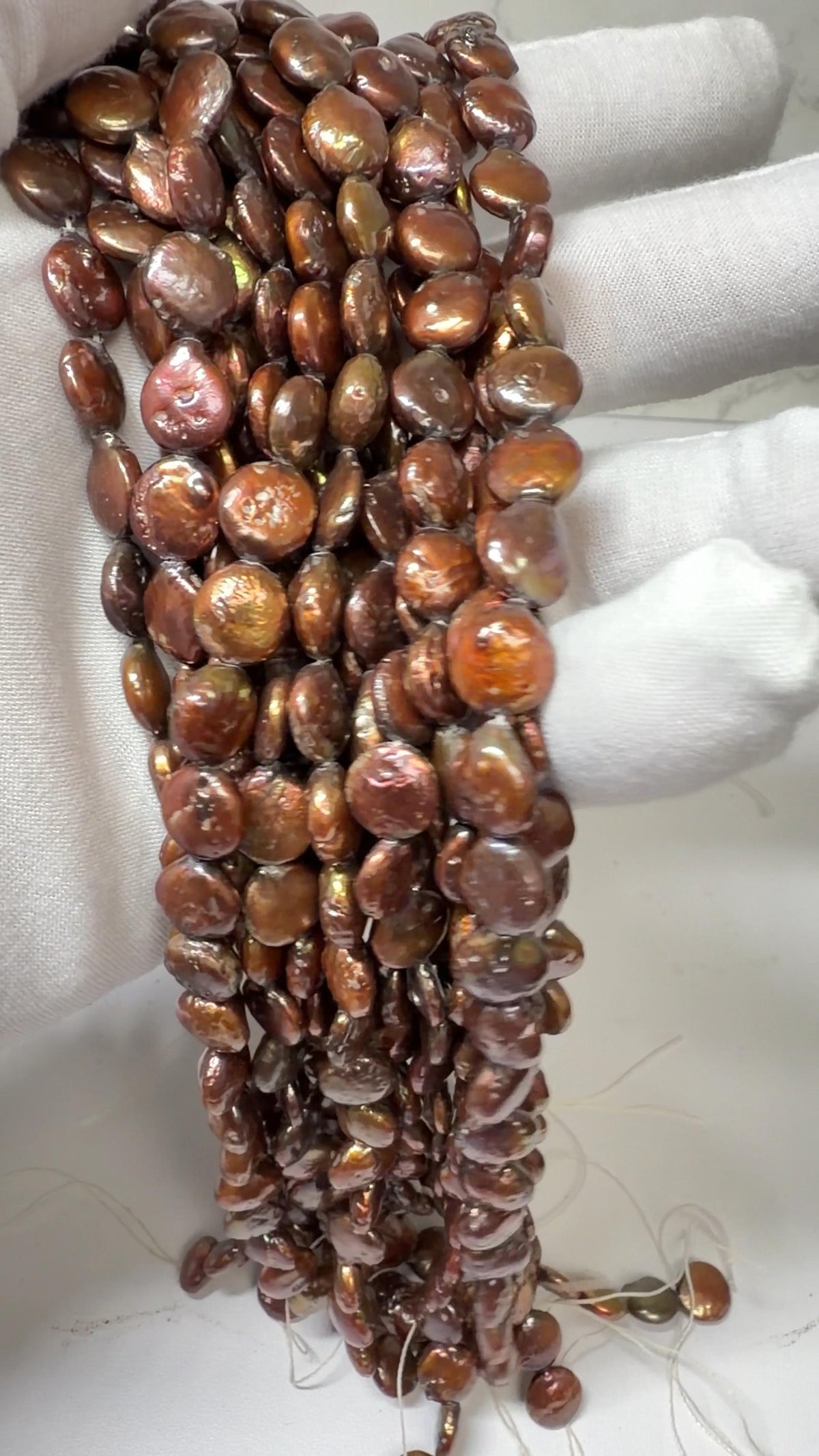 Coin Pearls Chocolate Color approx. 10mm, 15" strands!  Draped on a white gloved hand