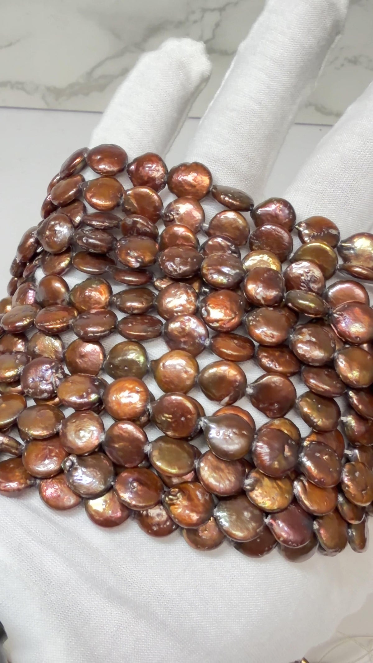 Coin Pearls Chocolate Color approx. 10mm, 15" strands!  Draped on a white gloved hand