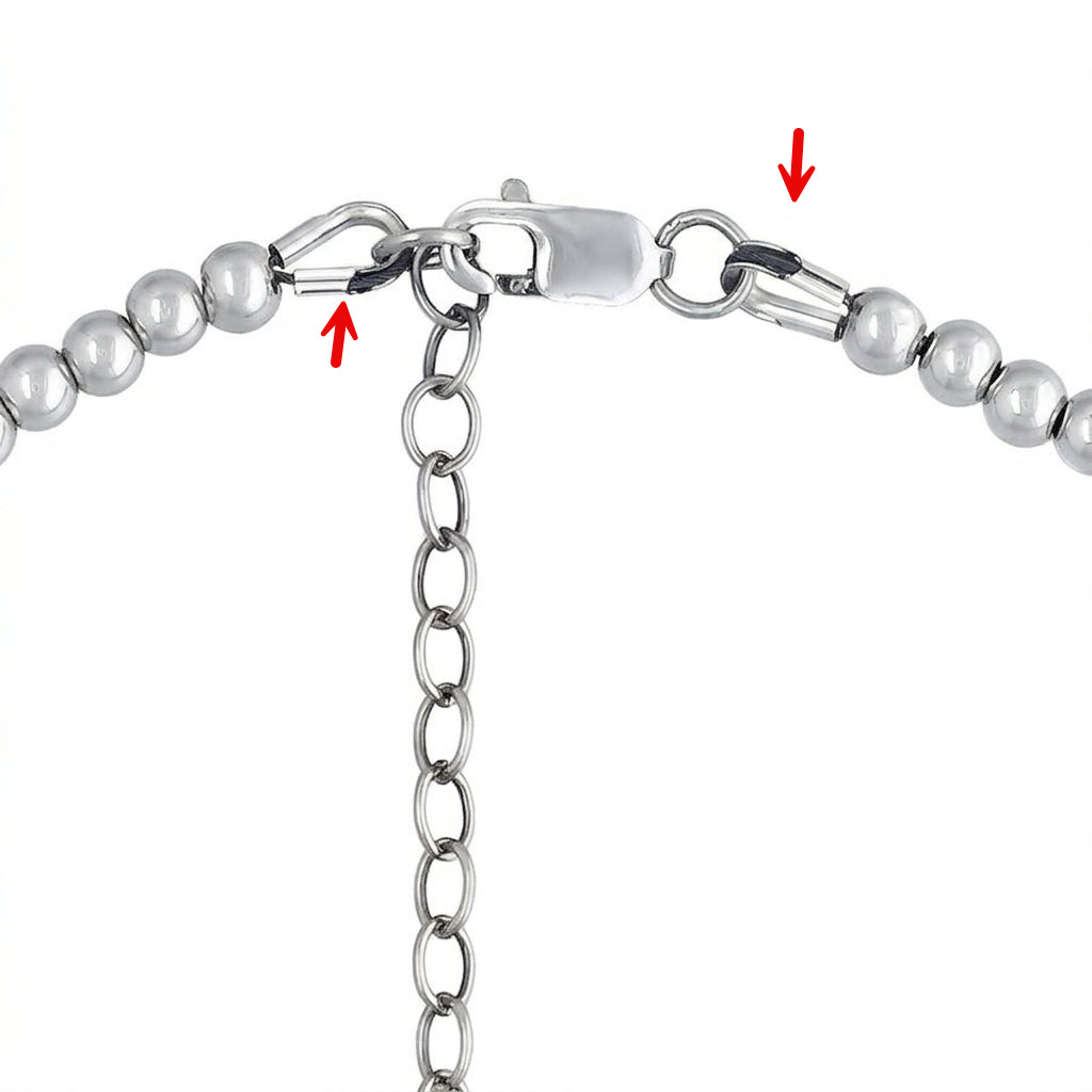 Close-up of a silver-toned beaded chain necklace clasp, showing the lobster clasp, extension chain, and ball beads, with red arrows pointing to the clasp area.