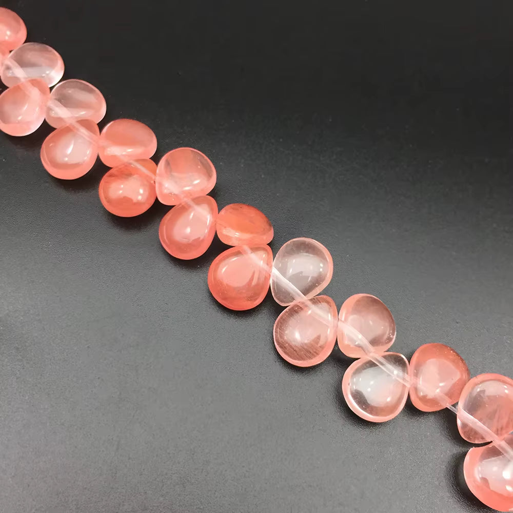 A strand of smooth, polished peach-pink gemstone beads on a dark gray background.