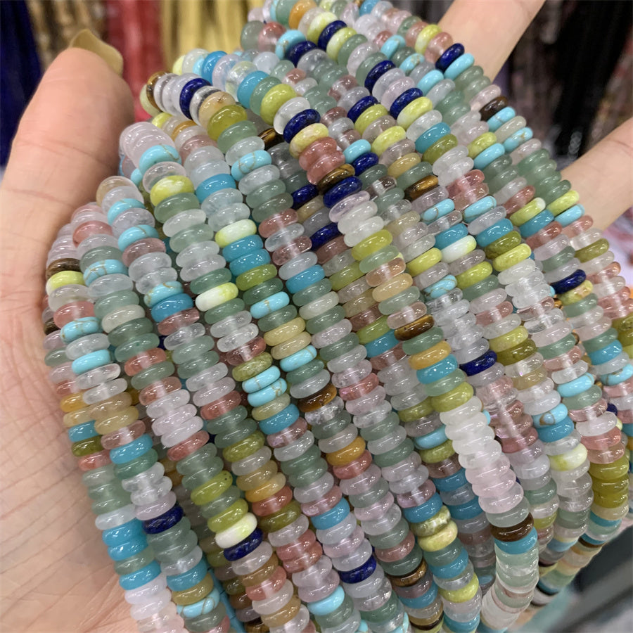 Assorted strands of 2x6mm spacer gemstone beads laid out over a hand
