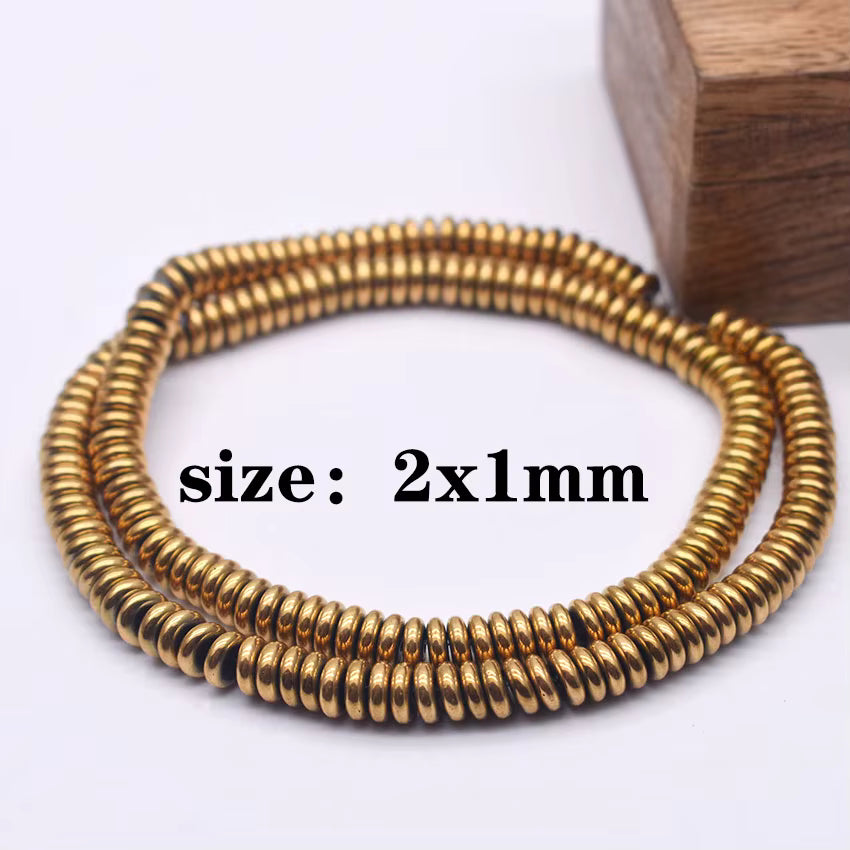 A coiled strand of small metallic gold beads, shown on a white background with a wooden block prop and overlaid text reading 'size: 2x1mm'.