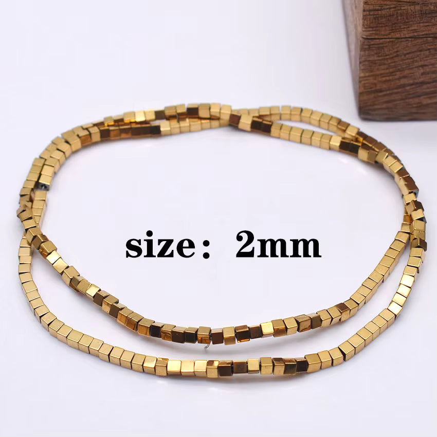 A coiled strand of small metallic gold cube beads on a white background, with red text reading 'size: 2mm' overlaid in the center.