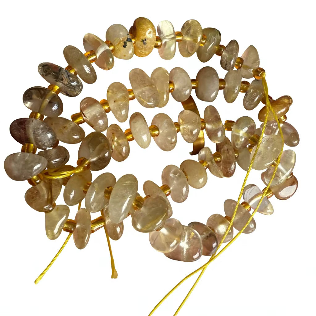 A coiled strand of polished tumbled gemstone beads in warm beige, brown, and smoky gray tones, strung on a gold cord against a plain white background.