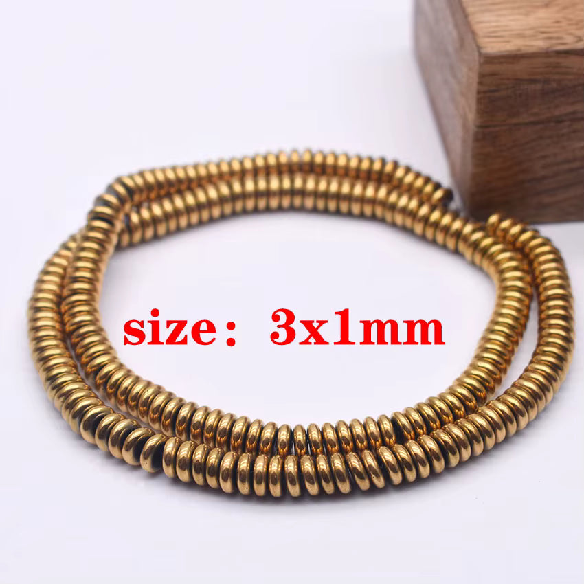 A strand of gold metallic beads, each 1 millimeter wide, arranged on a white surface with a wooden block in the background and red text reading 'size: 3x1mm'.