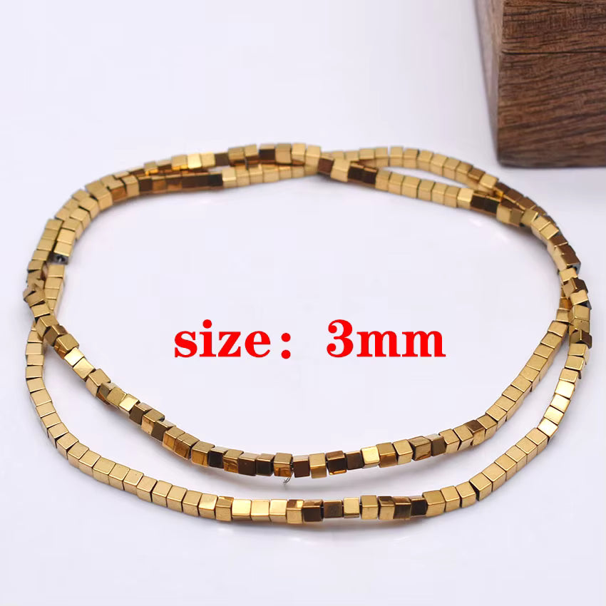 A coiled strand of small metallic gold cube beads on a white background, with red text reading 'size: 3mm' overlaid in the center.