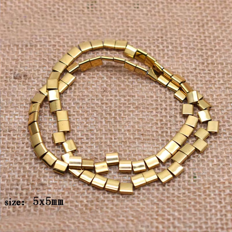 A coiled strand of small square gold beads, 5x5mm in size, displayed on a textured beige burlap background.