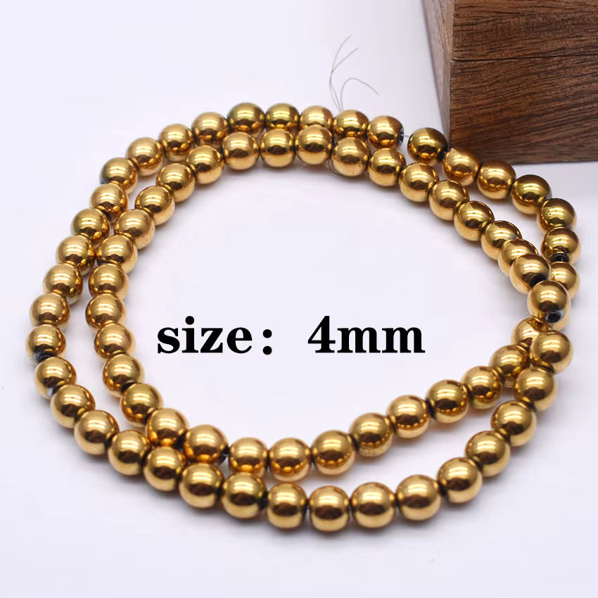 Three strands of shiny gold metallic 4mm round beads coiled on a white surface, with a wooden block in the background and 'size: 4mm' text overlaid in the center.