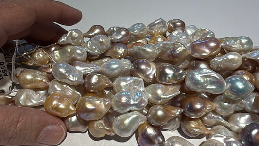 Collection of multicolored pearls on a white background with a hand for scale.