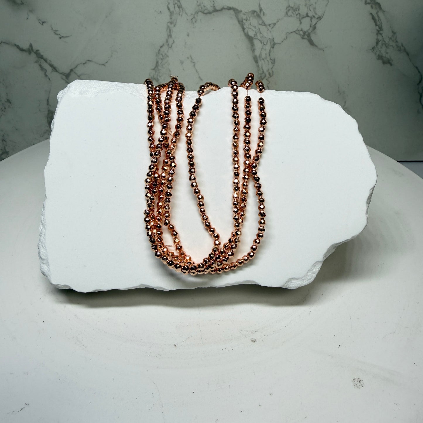 Hematite with Rose Gold PVD Finish.  Approx 15" Strands