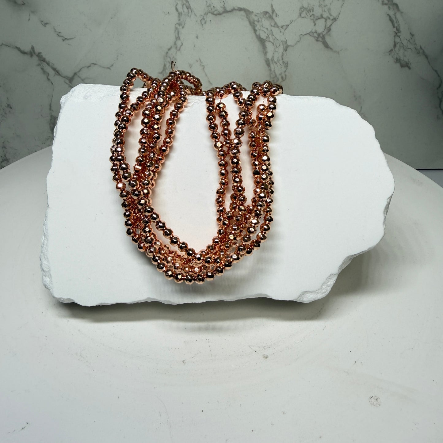 Hematite with Rose Gold PVD Finish.  Approx 15" Strands
