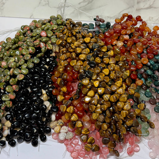 Multiple paddle shape gemstone beads on a strand on a white and marble background