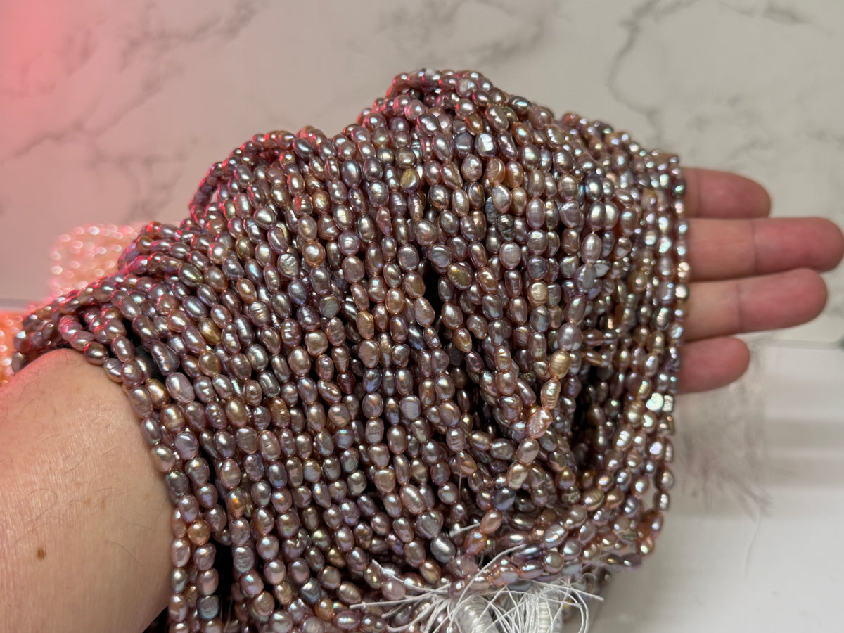Close-up of strands of irregular baroque pearls purple, draped over a hand.