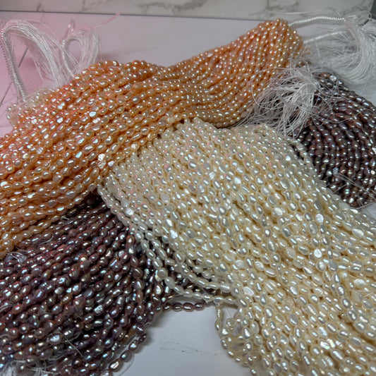 Close-up of strands of irregular baroque pearls in multiple colors, including lavender, cream, and peach, laid out over each other.