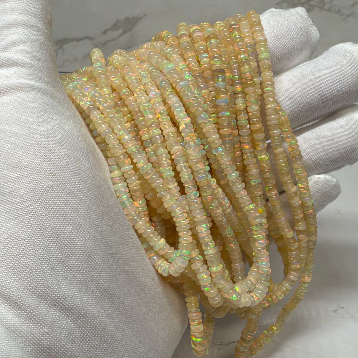 Multiple strands of opal beads over a white glove