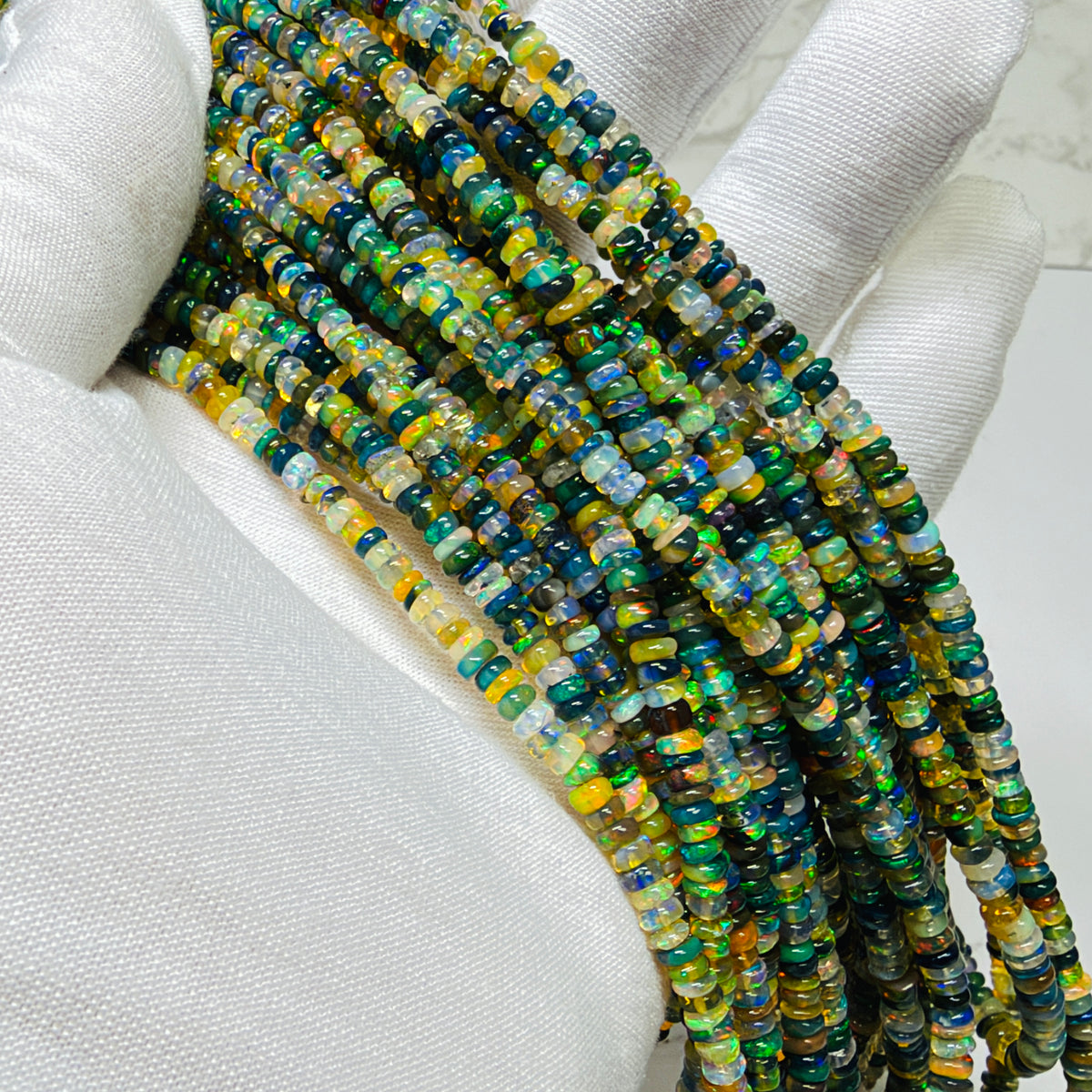 Strands of multi color opal beads on a white glove