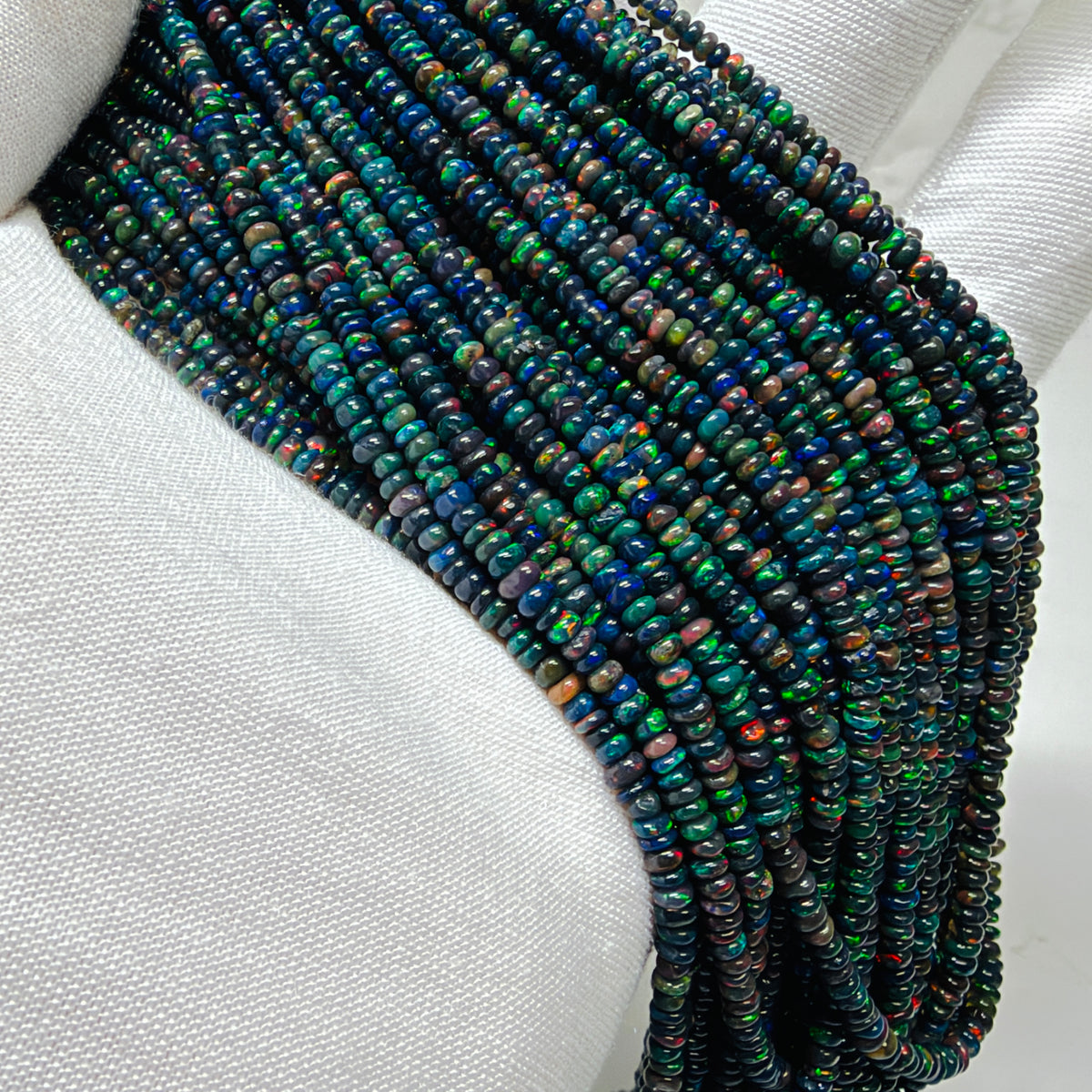 Strands of small Black opal beads on a white glove