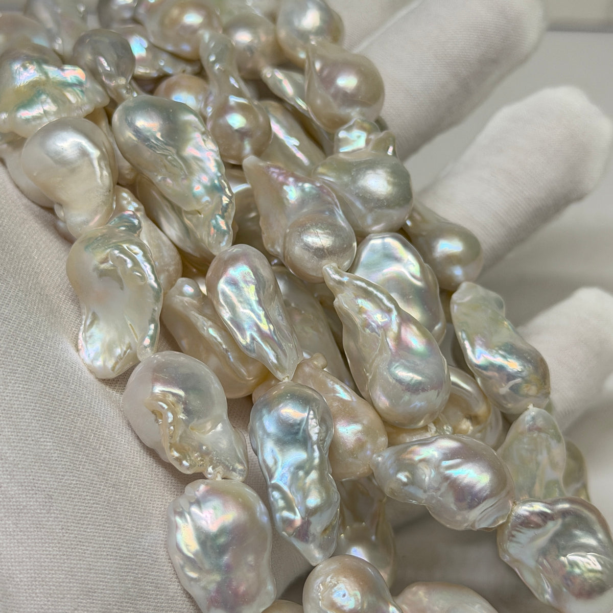 Close-up of iridescent baroque freshwater pearls draped over a white gloved hand.