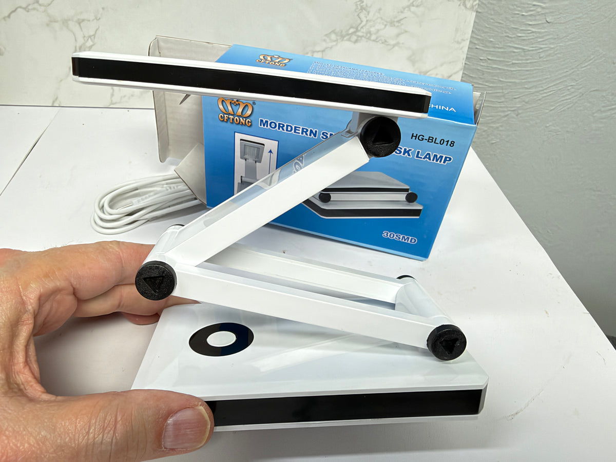 White folding LED desk lamp with its adjustable arm extended in a zigzag position.