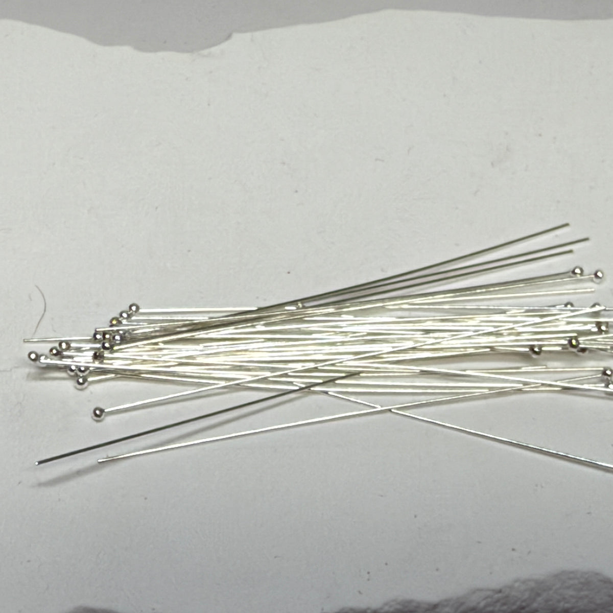 Overlapping sterling silver ball head pins showing slender wire shafts and small round ball ends.”