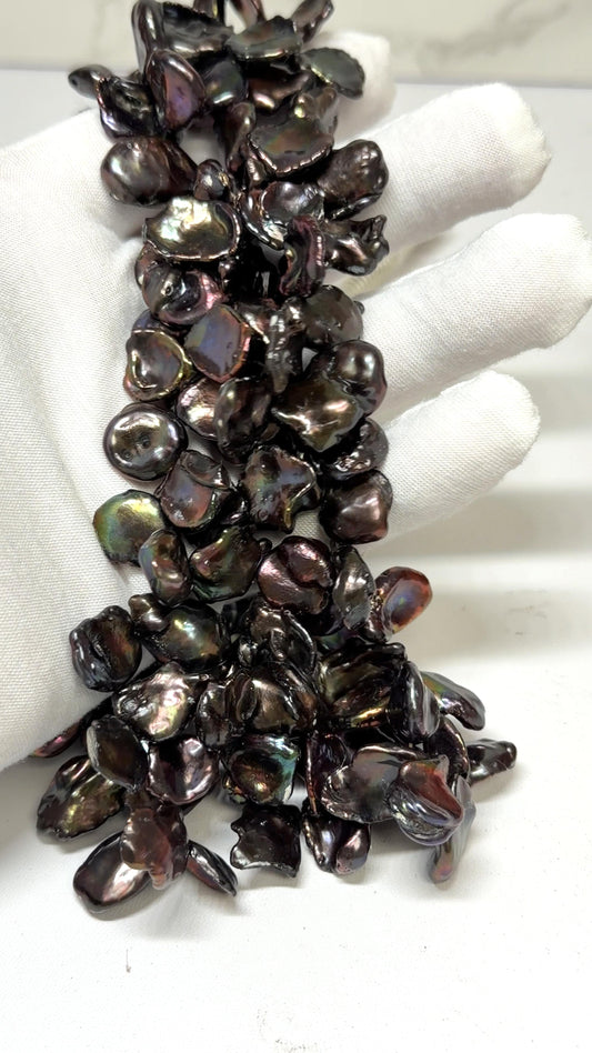 Keshi Peacock pearl strands draped over a white glove