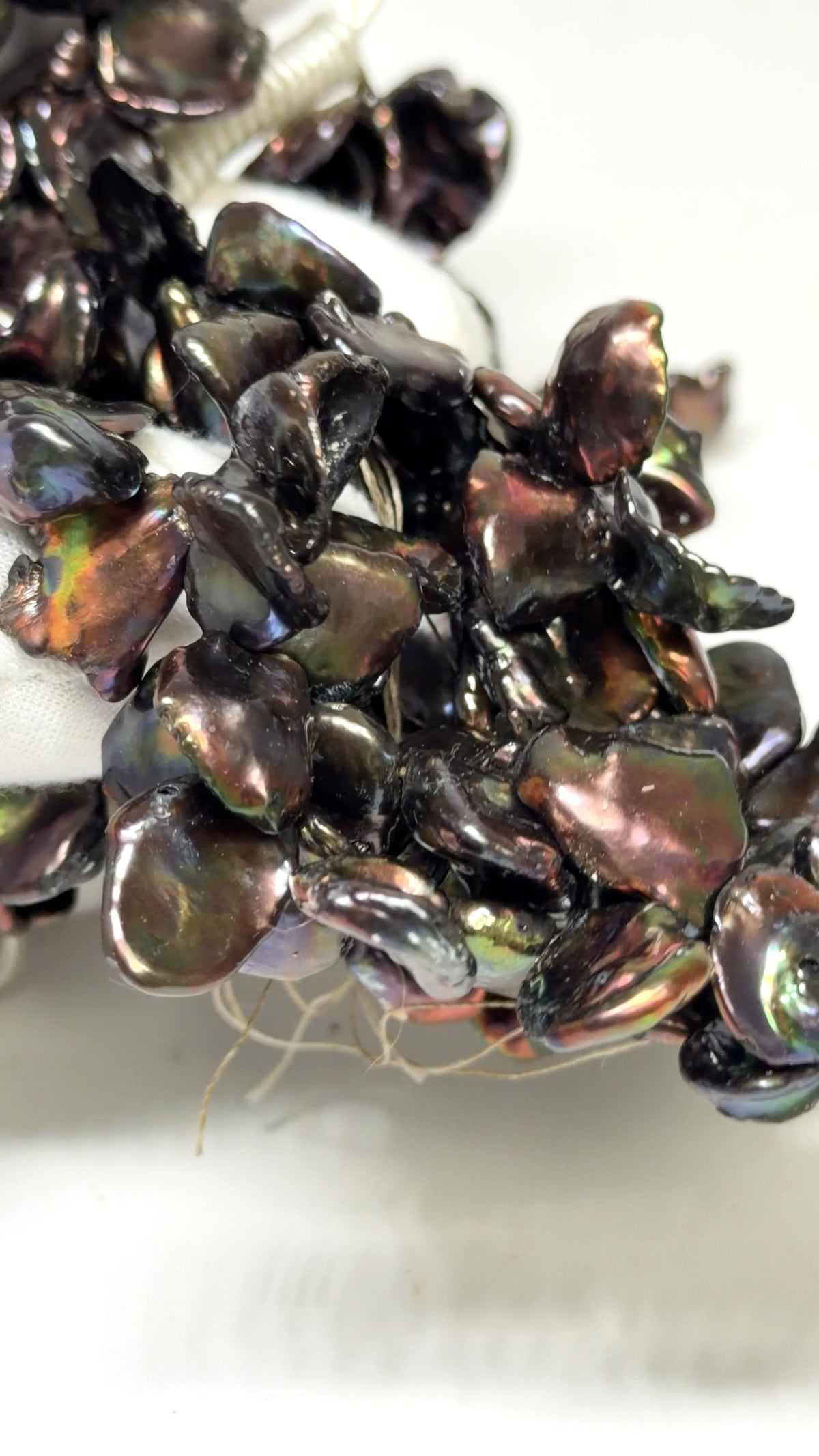 Keshi Peacock pearl strands draped over a white glove