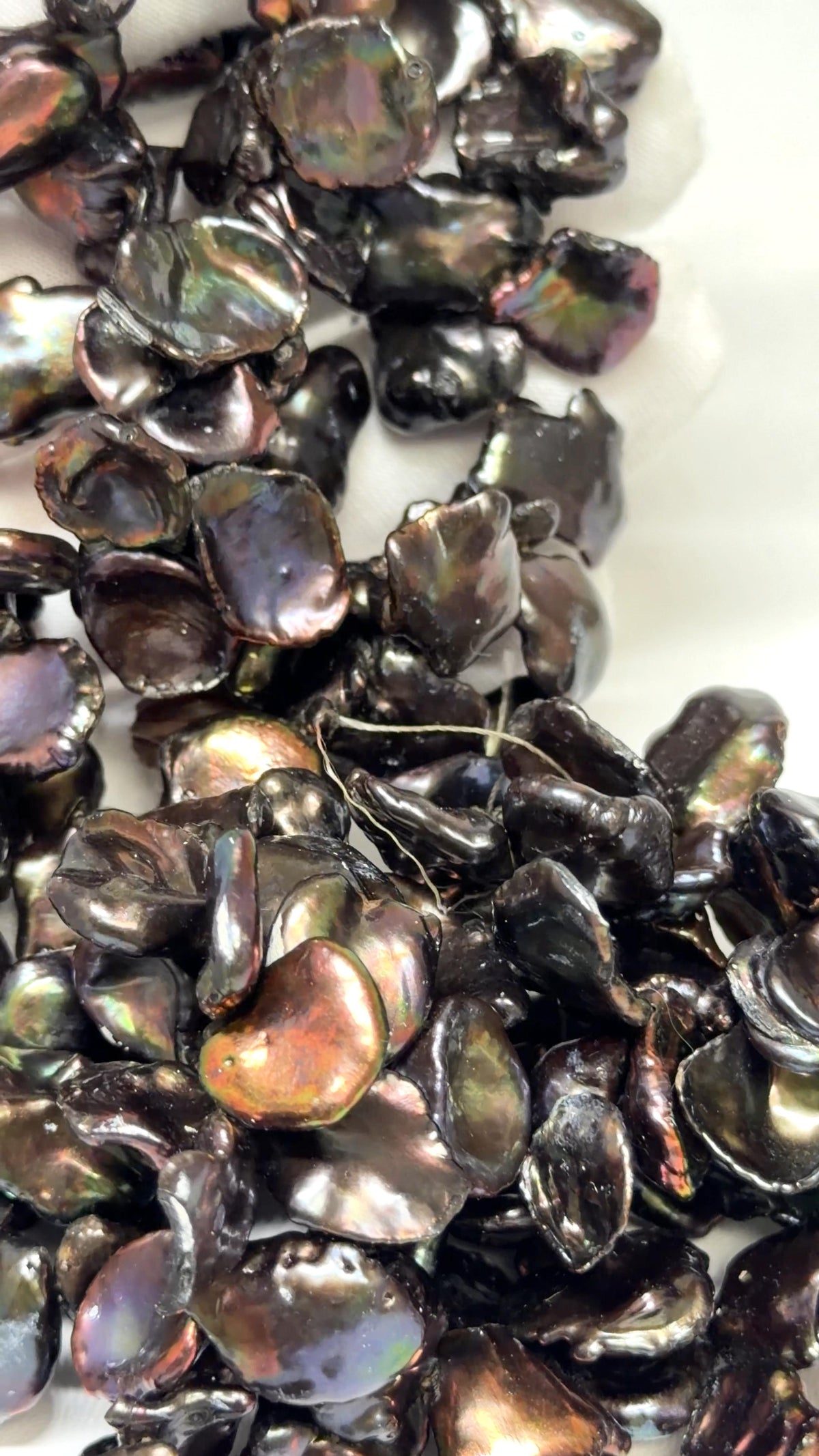 Keshi Peacock pearl strands draped over a white glove
