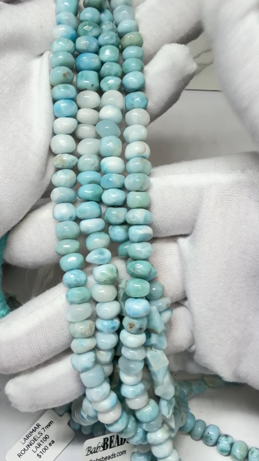 Larimar Roundel Bead Strands Draped over white gloved hands
