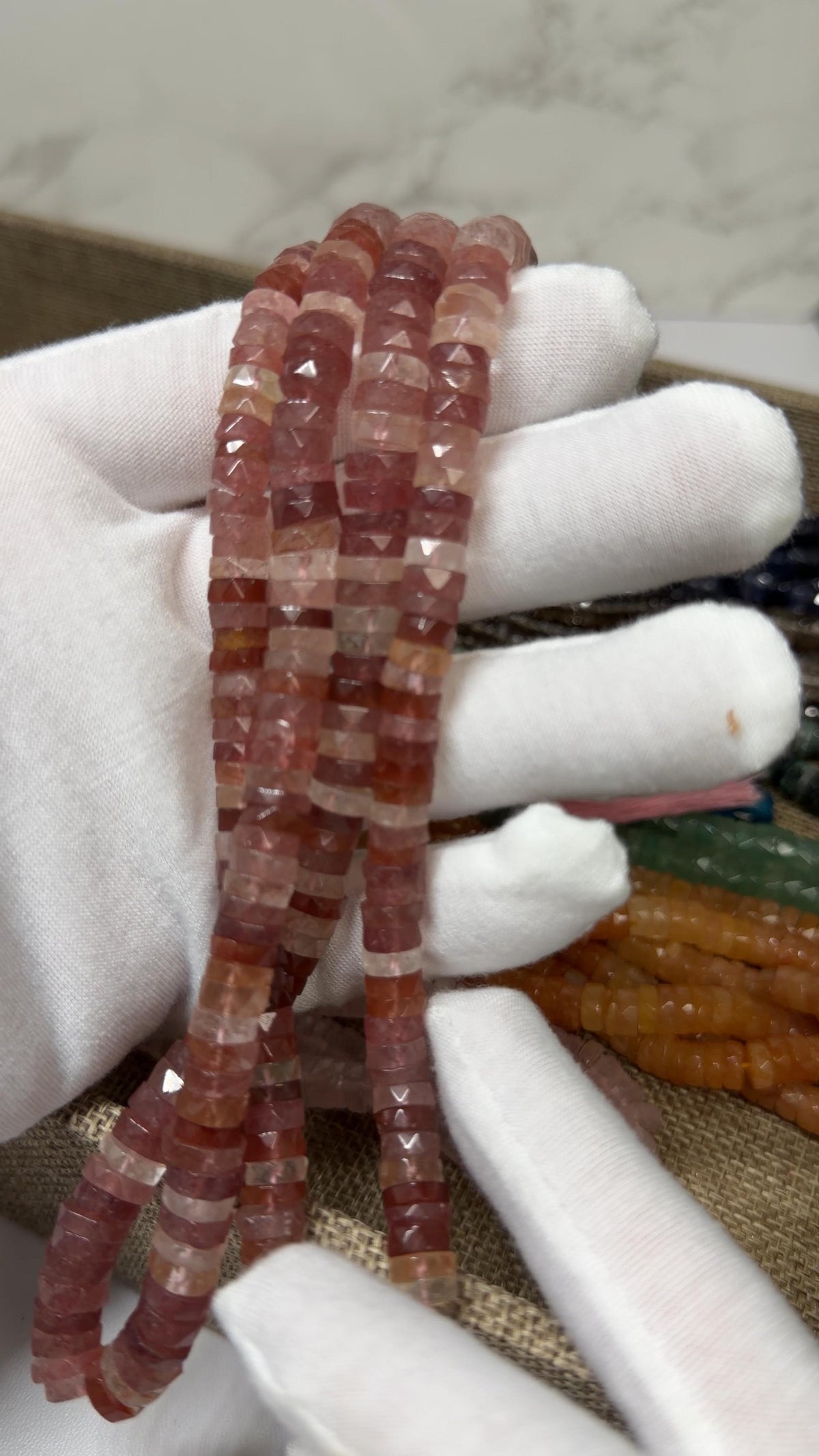 Strawberry Quartz Tire faceted tire shaped beads on a white glove hand