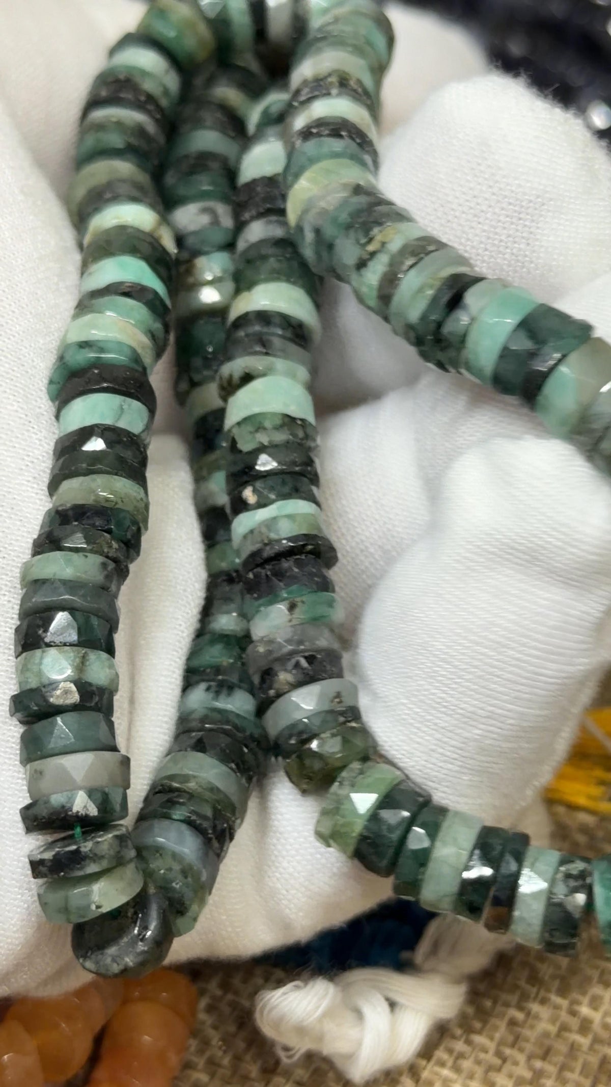 Green Tire faceted tire shaped beads on a white glove hand