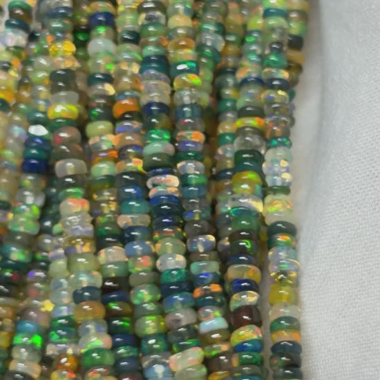 Video of strands of multi color opal beads on a white glove