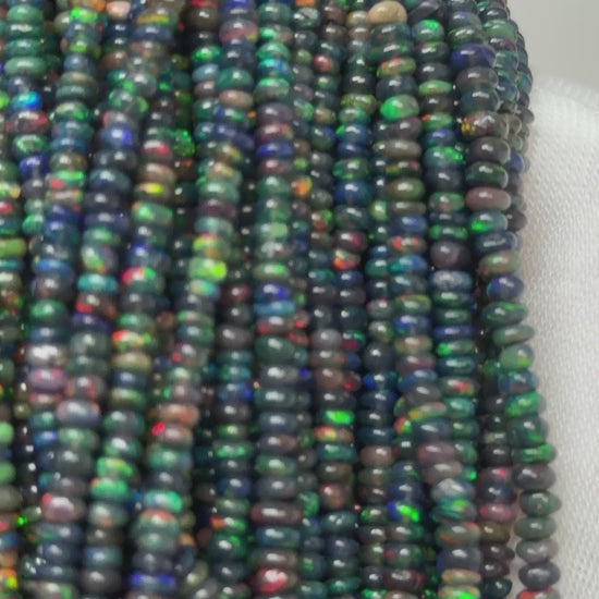 Video of small black opal strands of beads on a white glove