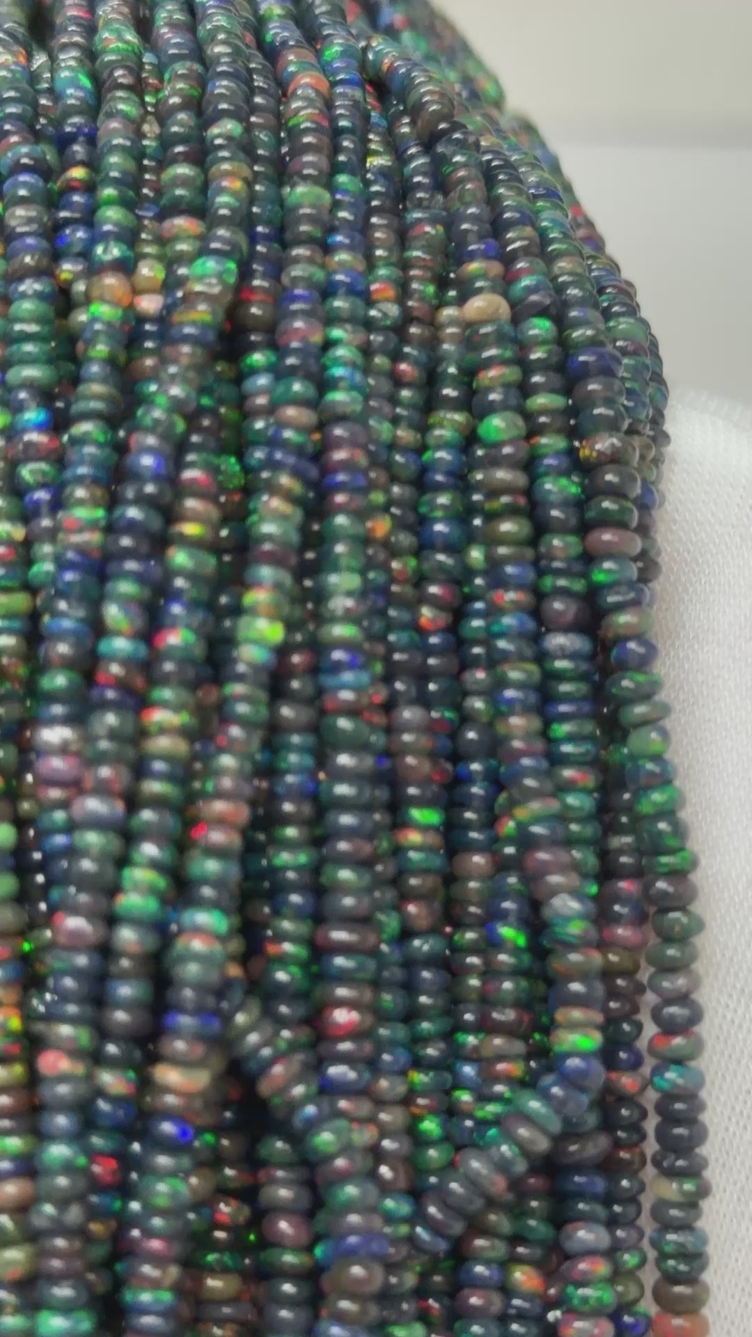 Video of small black opal strands of beads on a white glove